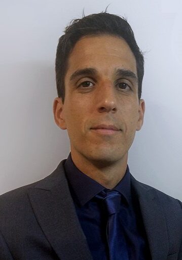 A man in a suit and tie standing against a wall.