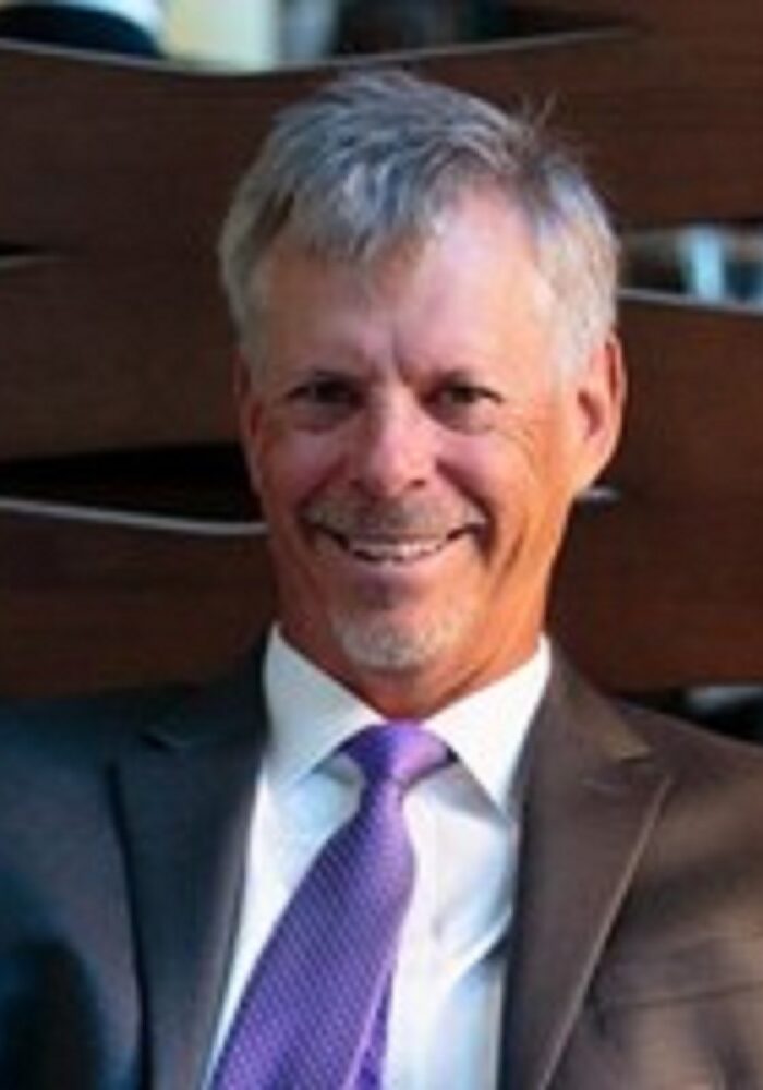 A man in suit and tie smiling for the camera.