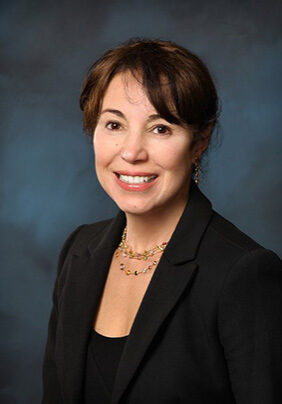 A woman in black jacket smiling for the camera.